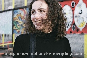 Vrouw met lang zwart haar en zwarte trui staat voor graffiti muur en is blij met vaak plassen door stress behandeling.