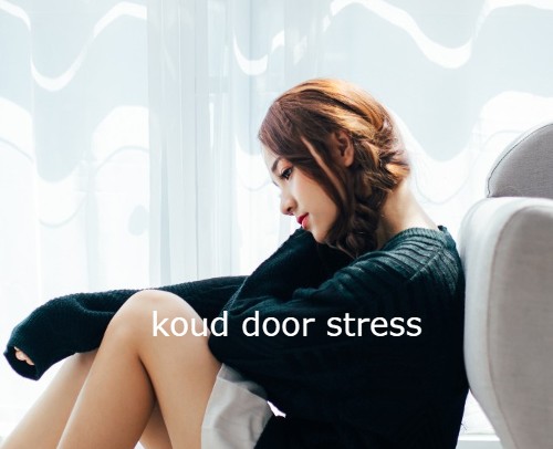 Vrouw met lang haar in vlecht en dikke donkerblauwe trui aan heeft het koud door stress.