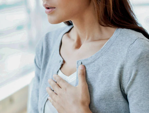 Vrouw met grijs vest heeft last van oprispingen door stress.