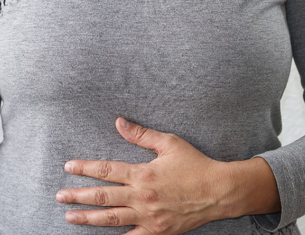 Vrouw met grijs shirt heeft last van rommelende darmen door stress oorzaken.