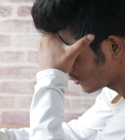 Man met wit overhemd en donker haar heeft last van stress hoofdpijn symptomen.